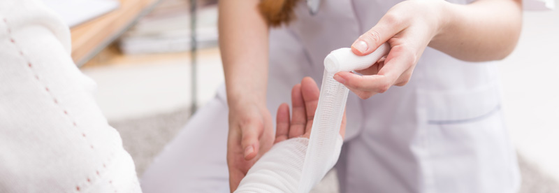 Une infirmière réalise un bandage sur le bras d'un patient