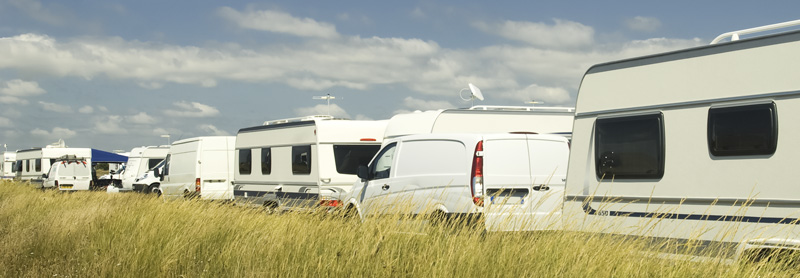 Des caravanes et des fourgons alignés sur une aire d'accueil des gens du voyage