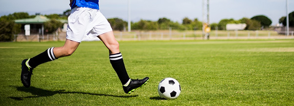 Une personne qui court avec un ballon aux pieds sur un terrain de football